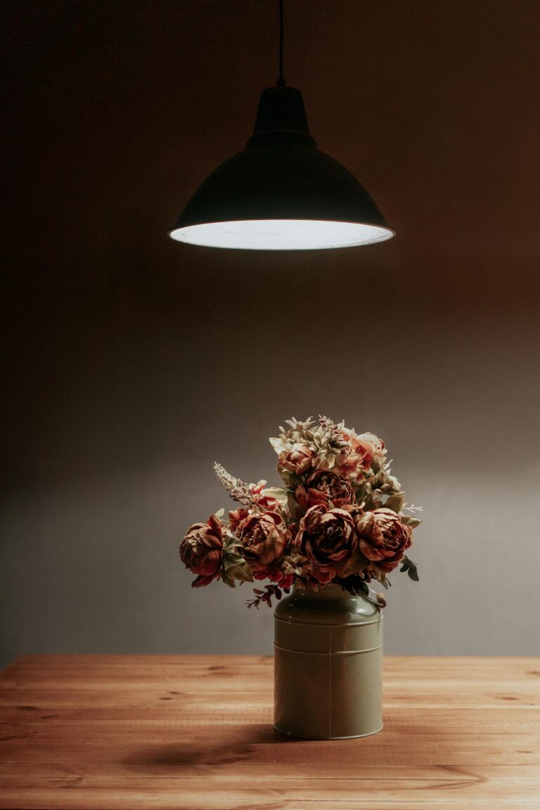 A warm, minimalist floral arrangement under soft lamp light, enhancing a cozy interior atmosphere.